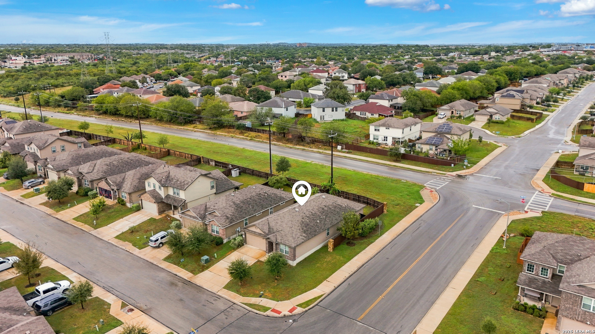 Aerial view of a marked corner-lot home among neighborhood houses and intersecting streets.