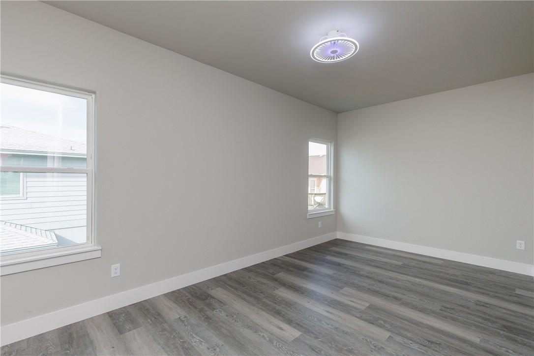 Vacant room with two windows, gray plank flooring, and a ceiling light.