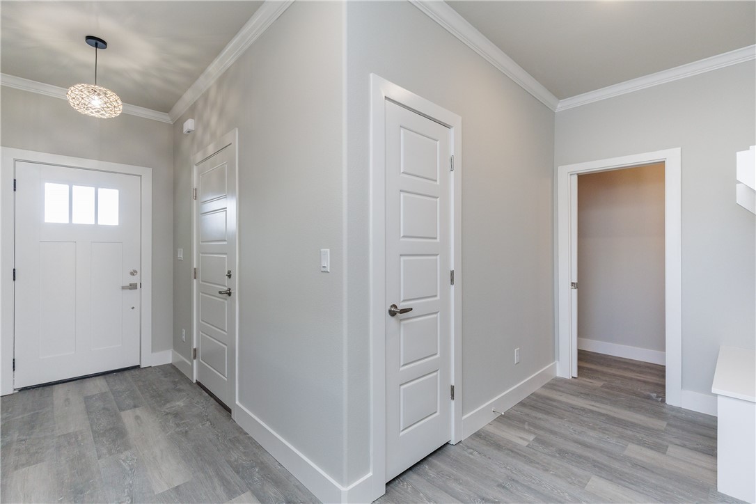 Entryway with gray plank flooring, white paneled doors, and a decorative pendant light.