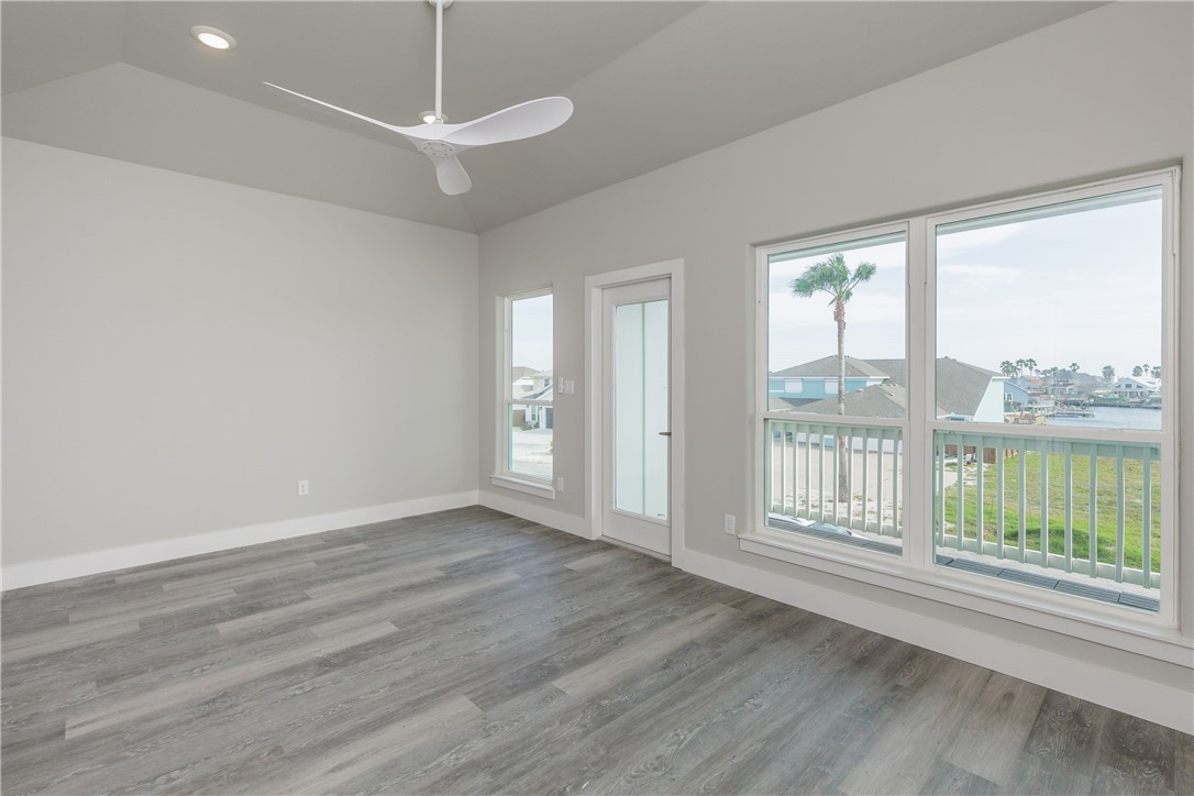 Vacant room with gray plank flooring and large windows overlooking a canal.