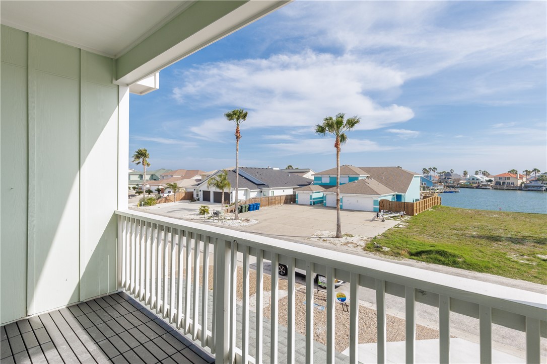 Covered balcony overlooking palm-lined homes and a canal.