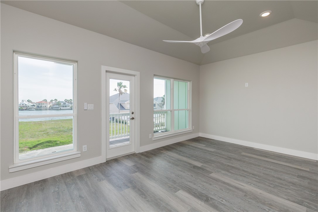 Empty living area with gray plank flooring and windows overlooking the water.