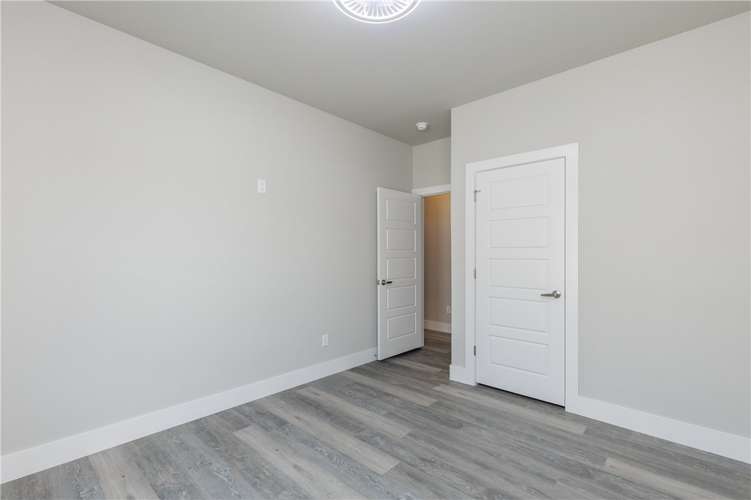 Empty room with gray plank flooring and two white paneled doors.