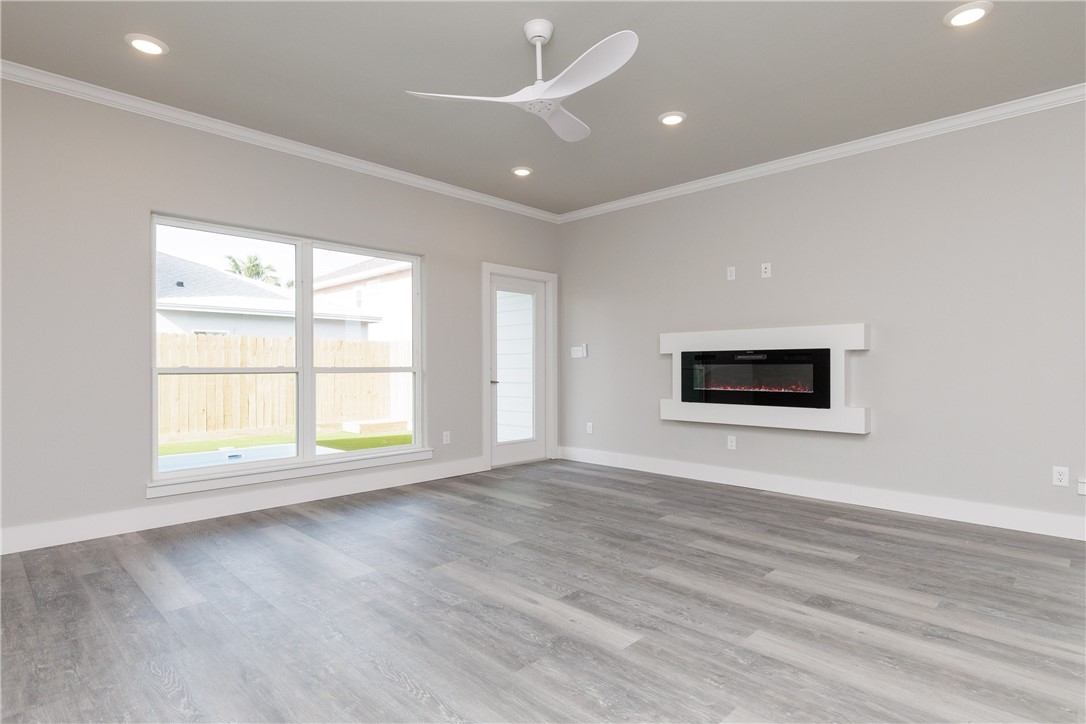 Vacant living room with gray plank floors, a wide yard-facing window, and a modern electric fireplace.