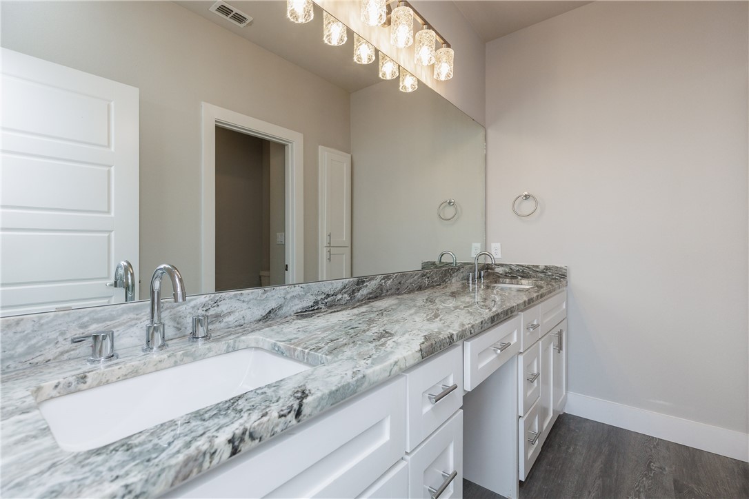 Bathroom vanity with gray-and-white stone counters, a large mirror, and pendant lights.