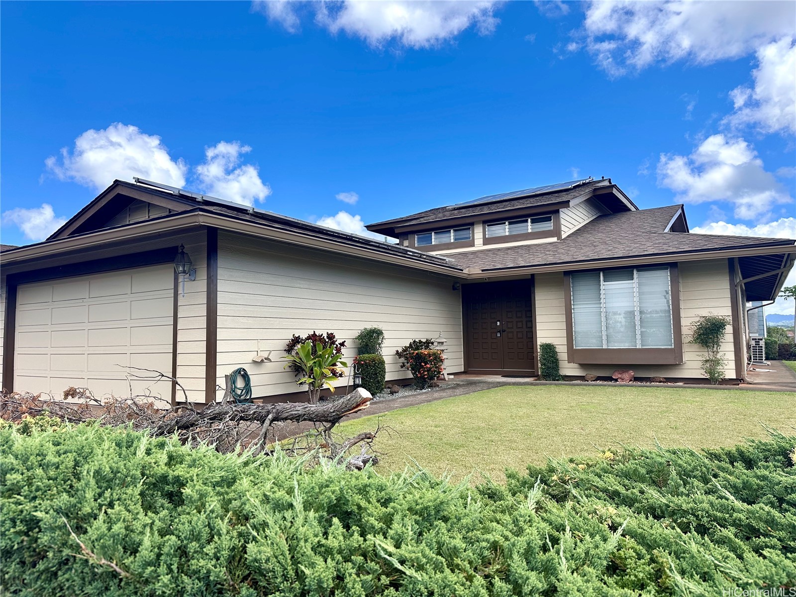 Two-story home with a two-car garage, rooftop solar panels, and a landscaped front yard.
