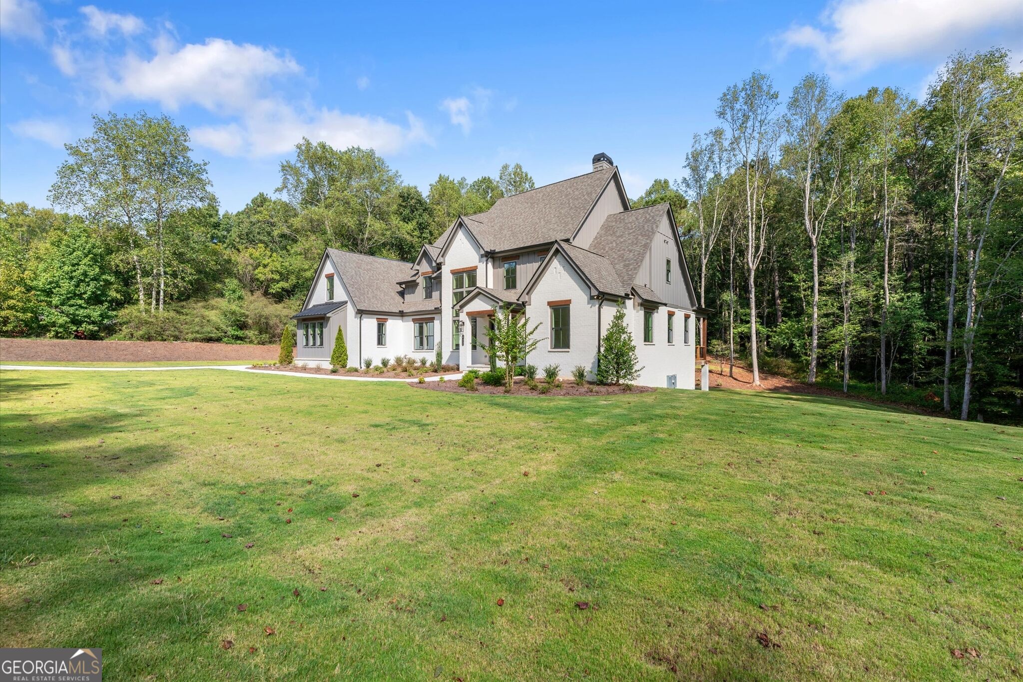 White multi-gabled house set behind a broad lawn, with mature trees along the property.