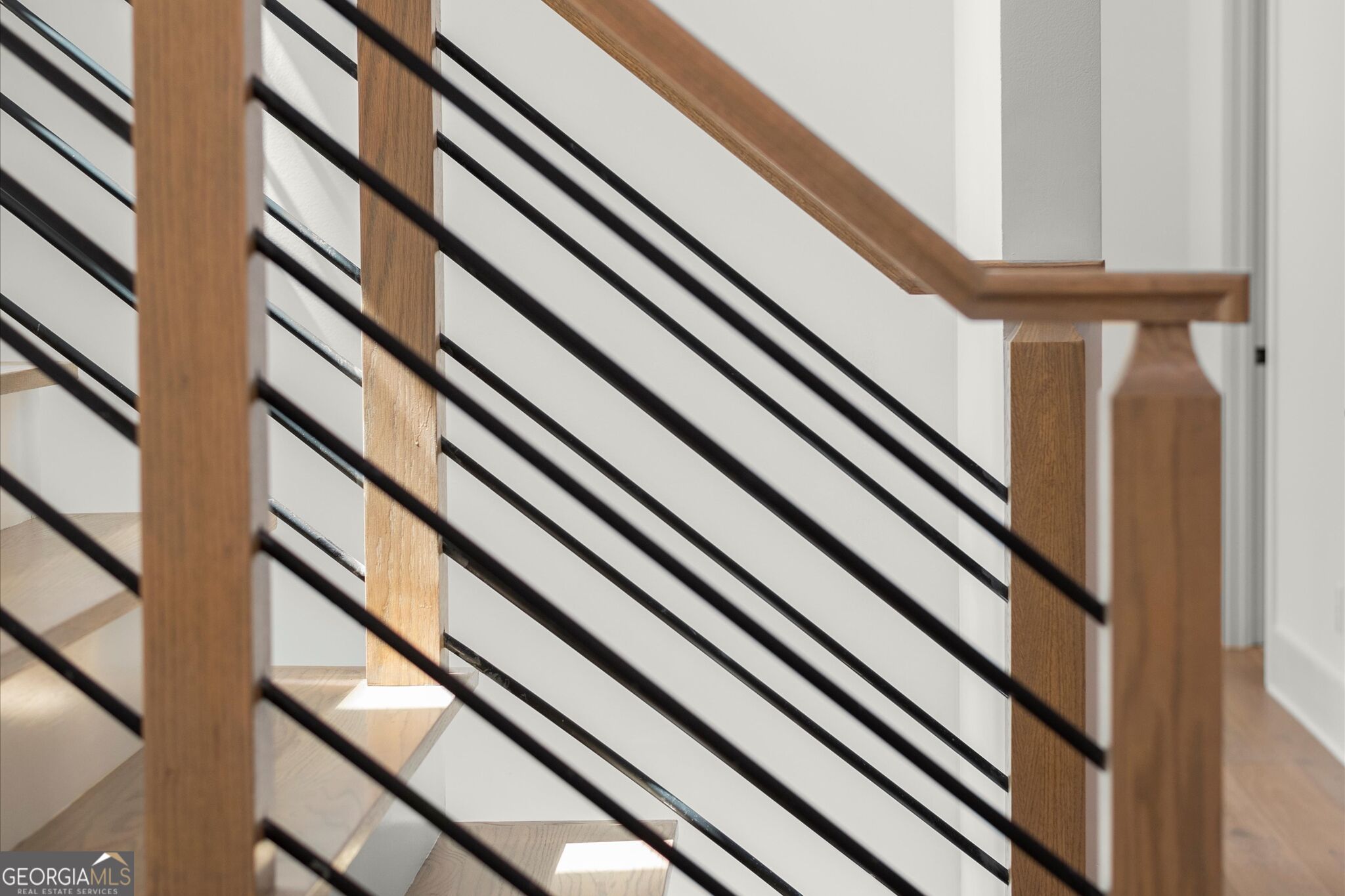 Staircase with light wood steps and posts and black metal railings.