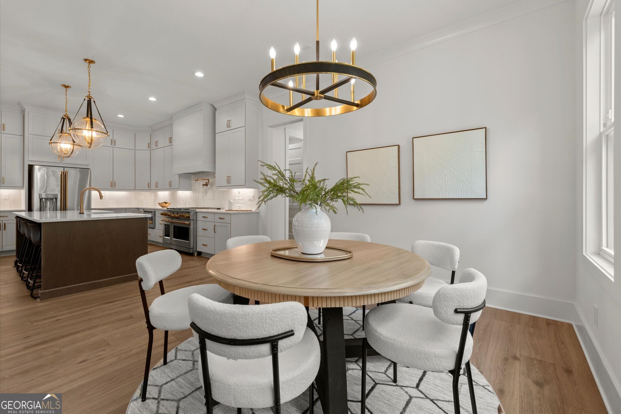 Open-plan kitchen and dining area with white cabinets, a dark island, and a round wood table.