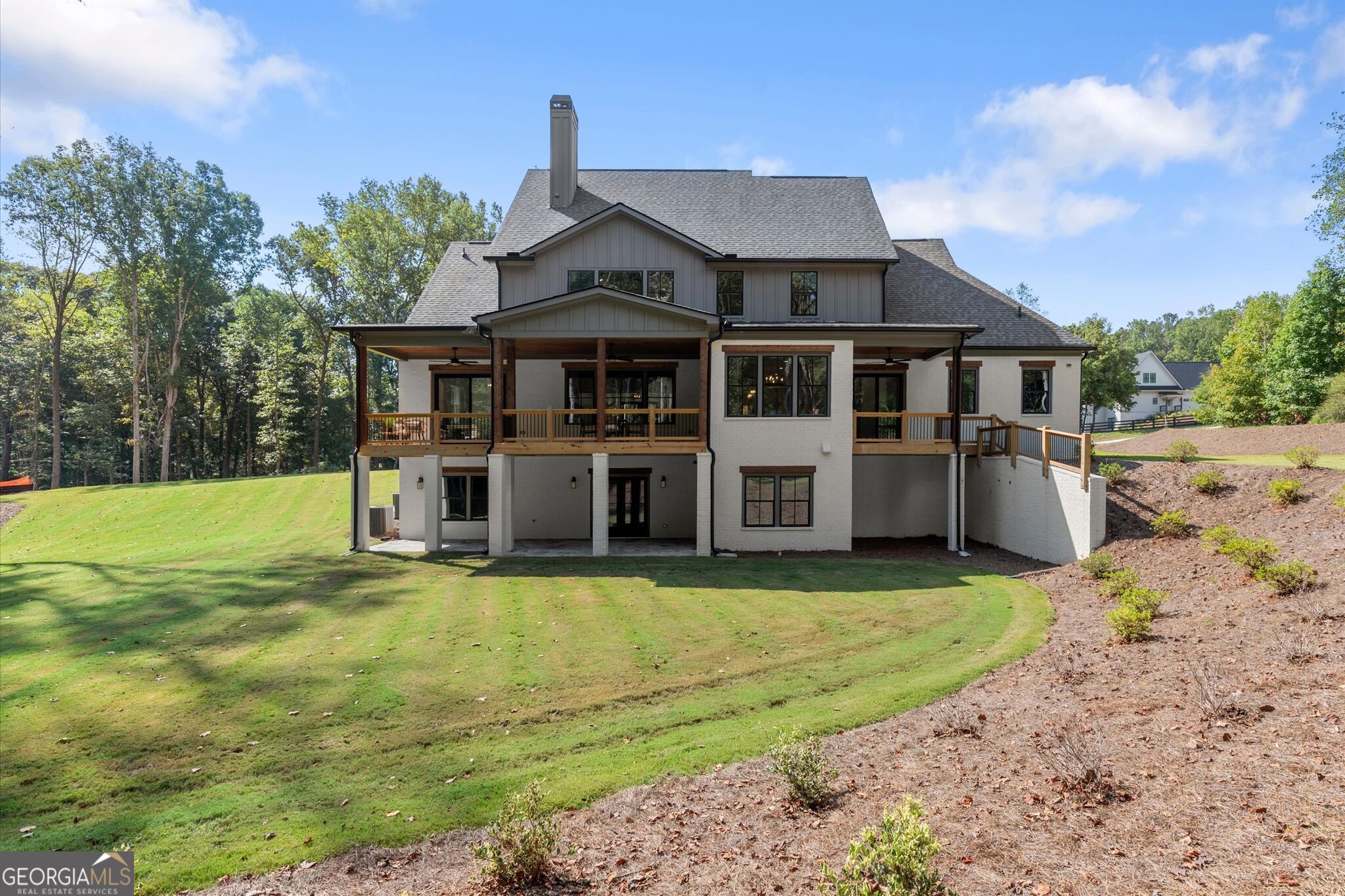 Rear of a two-story house with a covered deck, walkout lower level, and broad lawn.