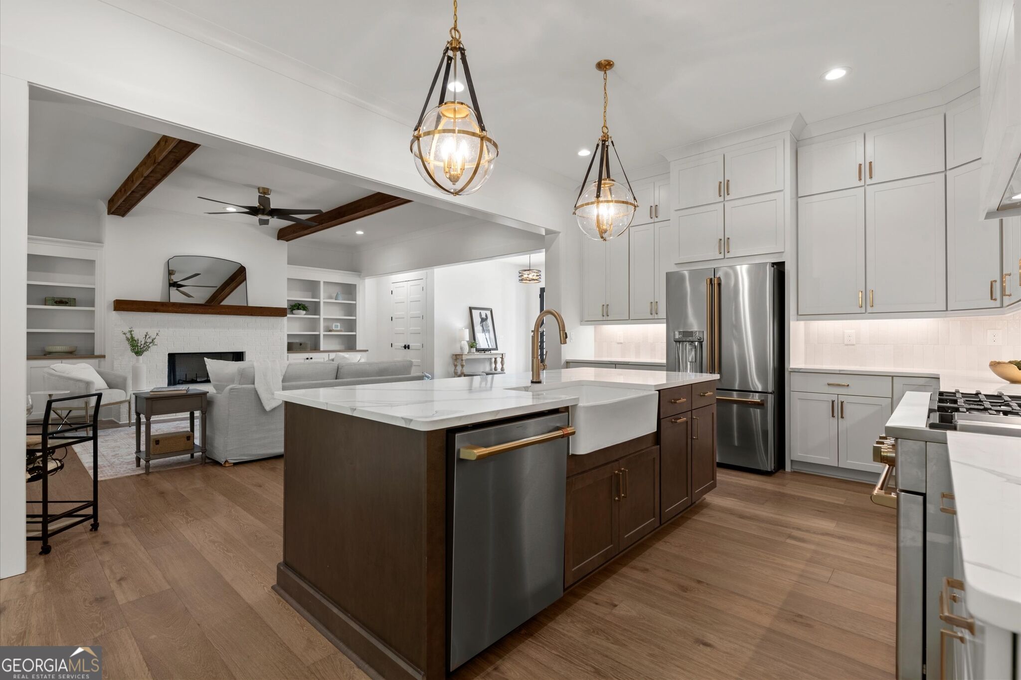 Open-plan kitchen with a large dark-wood island, white cabinets, and an adjoining living room with a fireplace.