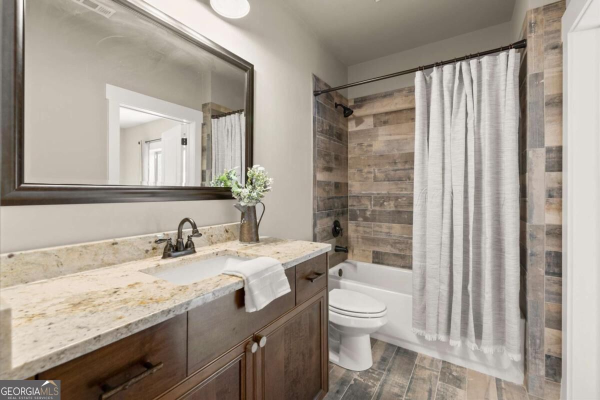 Bathroom with a wood-finish vanity and a tub-shower with multicolored wood-look tile.