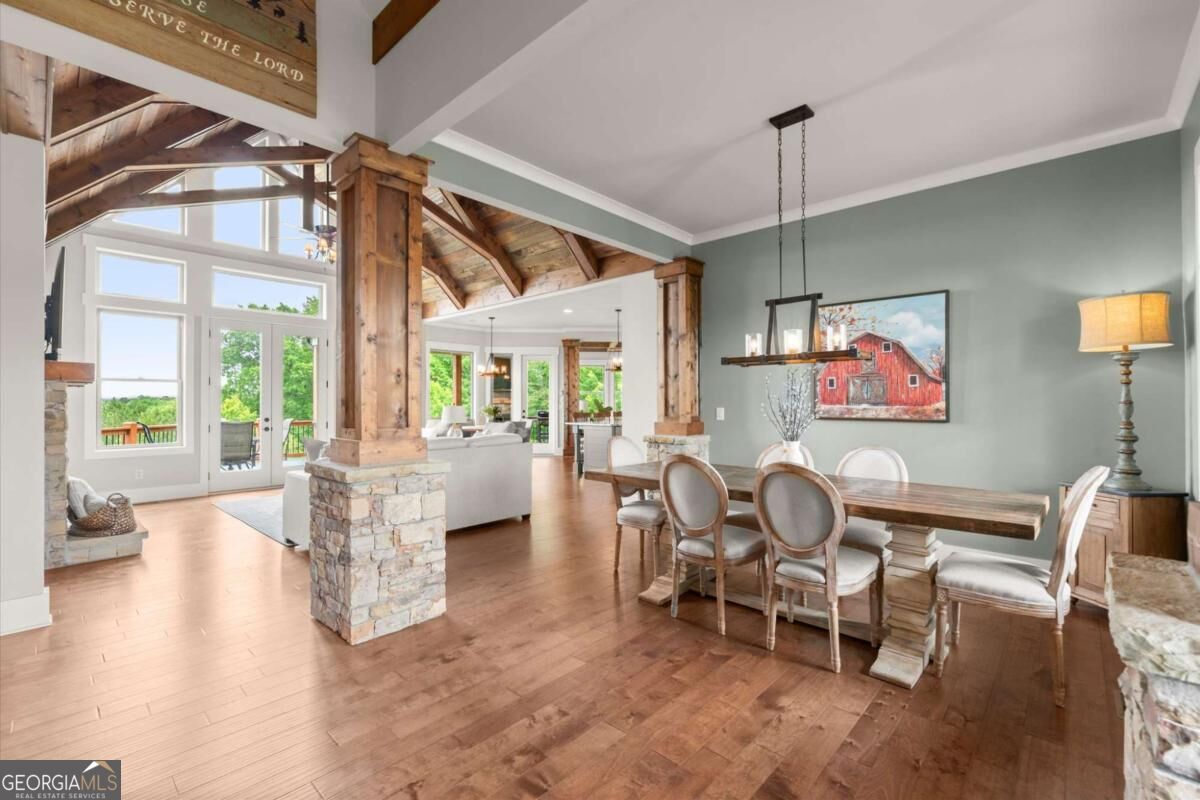 Open-plan dining room with exposed timber ceiling, stone columns, and large windows overlooking greenery.