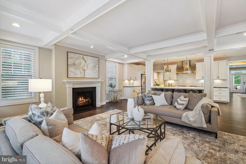 Open-plan living room with gray sofas, a fireplace, and a kitchen with white cabinetry.