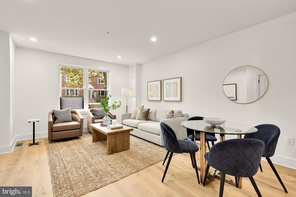 Staged living and dining room with a cream sofa, navy dining chairs, and large windows.
