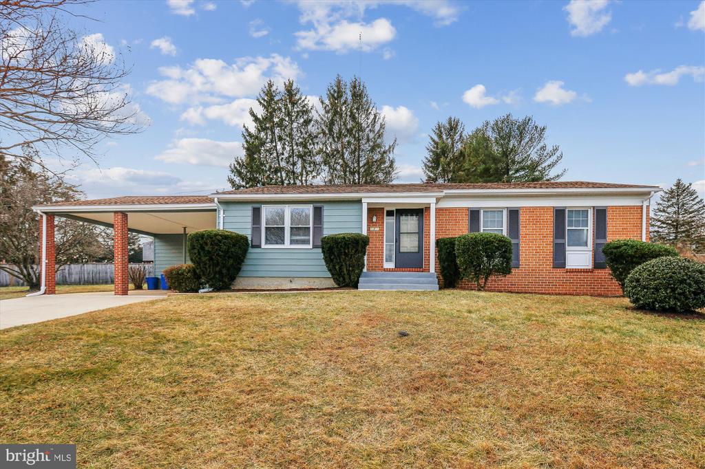 Single-story ranch home with red brick, pale blue siding, and a covered carport.