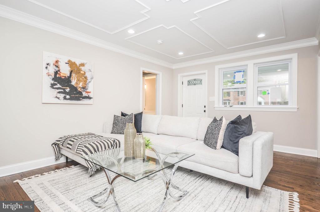 Staged living room with a white sectional, glass coffee table, and abstract wall art.