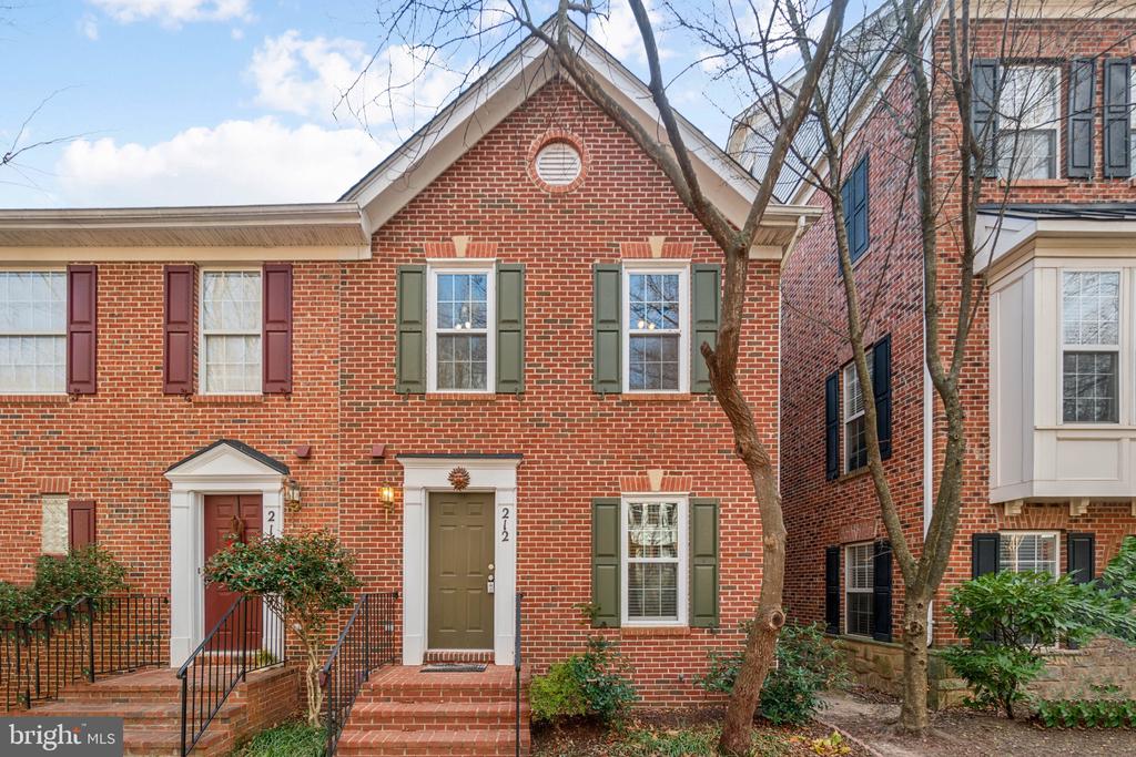 Red-brick townhouse with green shutters, a front gable, and brick entry steps.