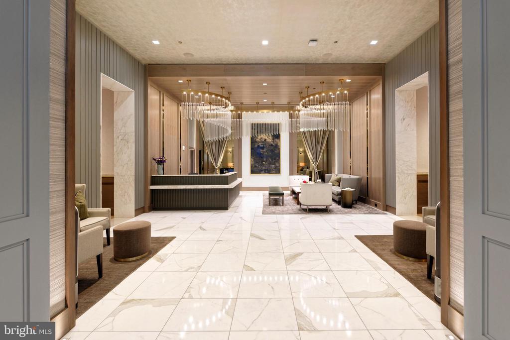 Upscale lobby with a marble floor, reception desk, lounge seating, and tiered chandeliers.