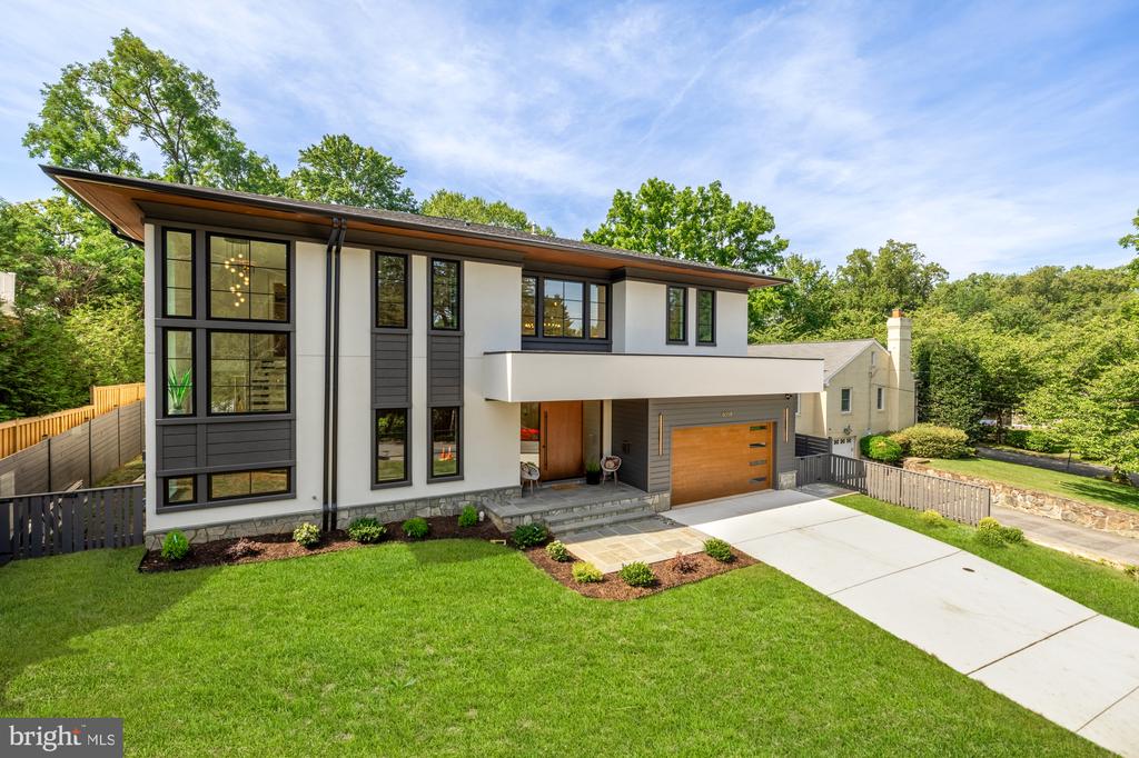 Modern two-story home with charcoal siding, large windows, and a wood garage door.