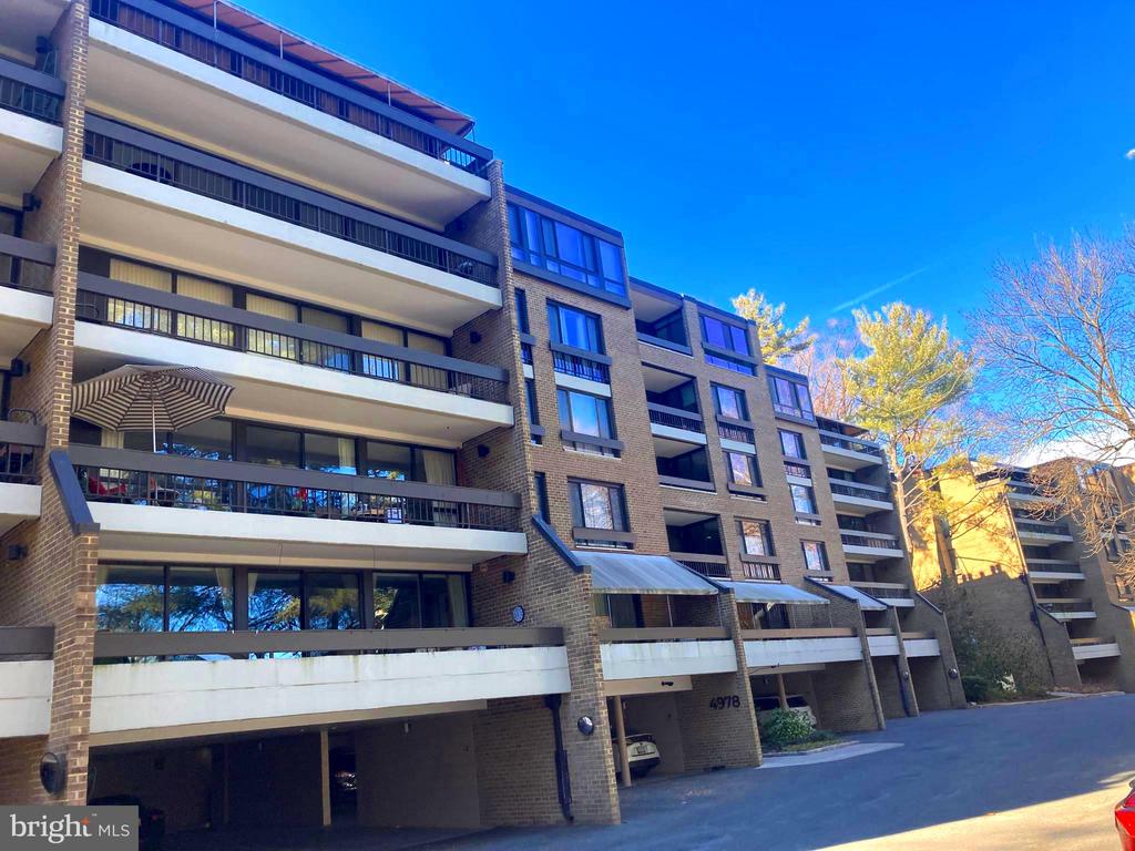 Brick condominium building with stacked balconies and the number 4978 above its entrance.