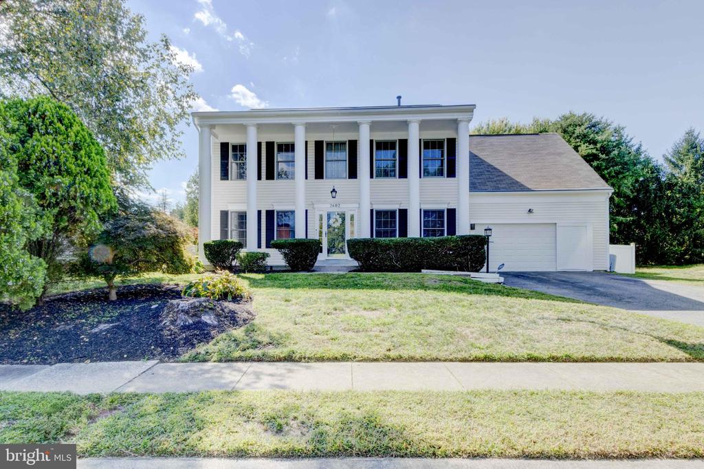 White two-story Colonial home with tall columns, black shutters, and an attached garage.