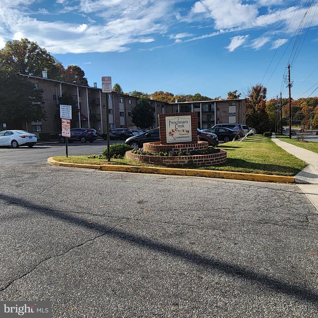 Frenchman's Creek condominiums entrance sign and multi-unit buildings beside a parking lot.