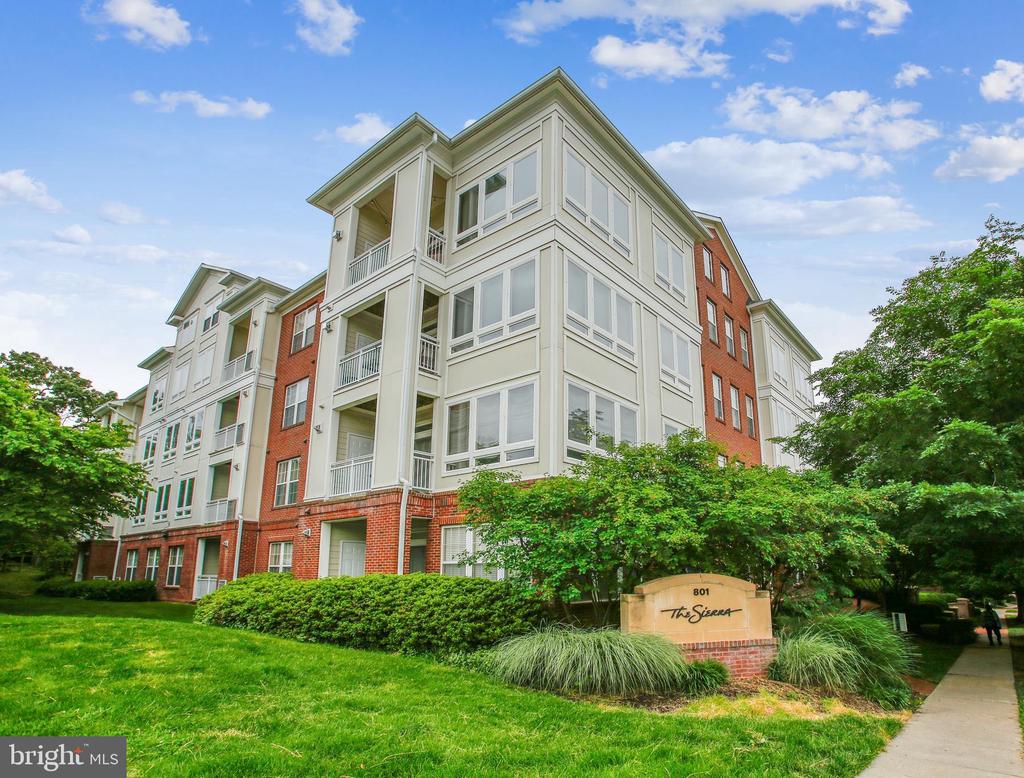 The Sierra condominium building with white siding, red brick, balconies, and a landscaped lawn.