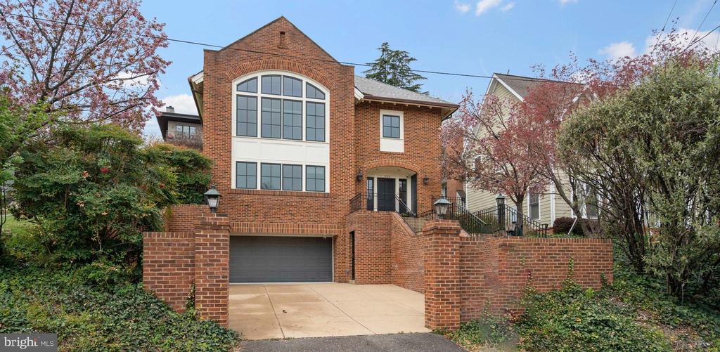 Red brick home with an arched front window, attached garage, and flowering trees.