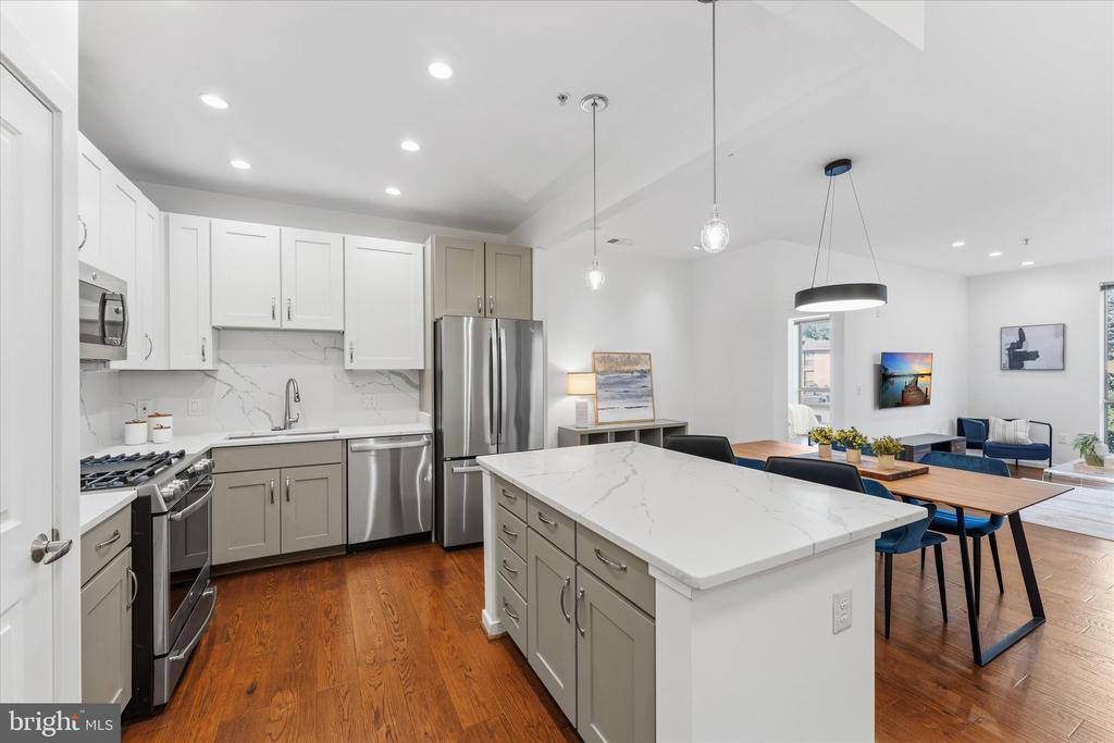 Modern kitchen with a large marble island, stainless steel appliances, and an adjoining dining area.