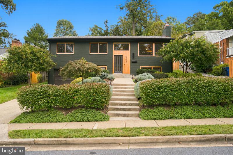 Dark green split-level home with broad front steps and neatly clipped hedges.