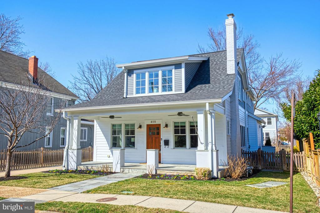 Gray two-story house with a covered porch, dormer windows, and a prominent white chimney.