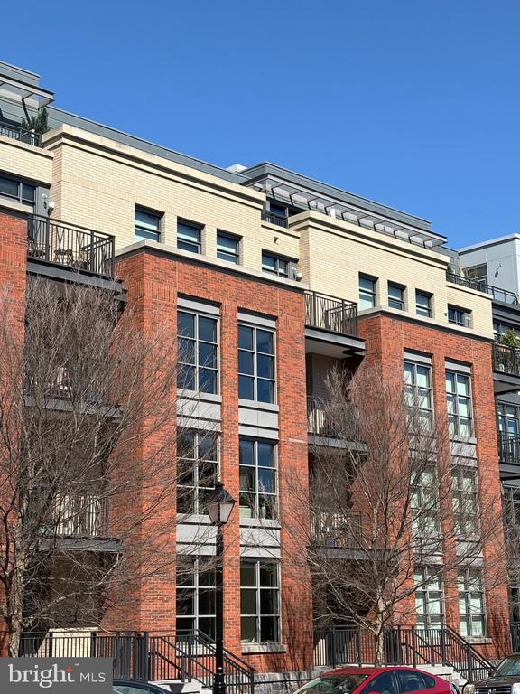Multi-story red brick and pale stone residential building with balconies and large windows.