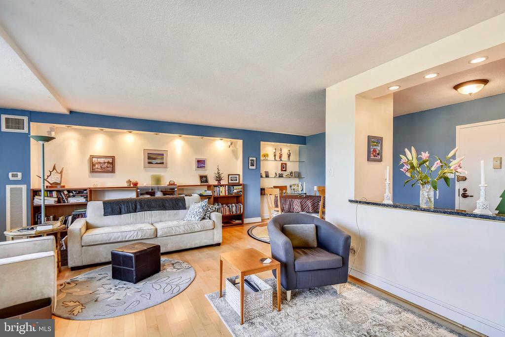 Living room with blue walls, a cream sofa, bookshelves, and a dining area beyond.
