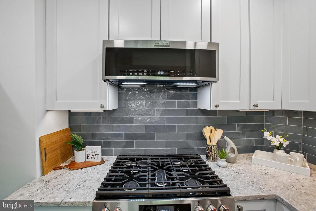 Kitchen with a gas cooktop, white cabinetry, and dark gray tile backsplash.