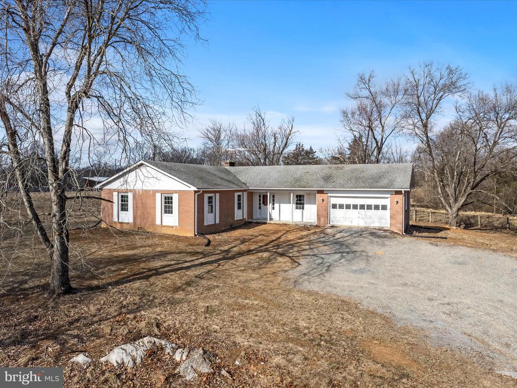 Brick ranch house with an attached two-car garage at the end of a gravel driveway.