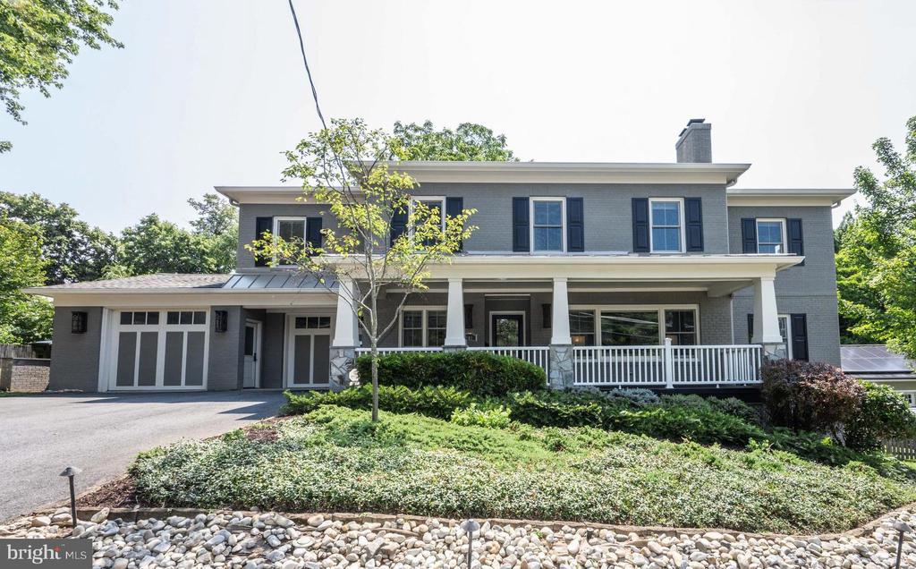Gray two-story house with a covered porch, attached garage, and landscaped front yard.