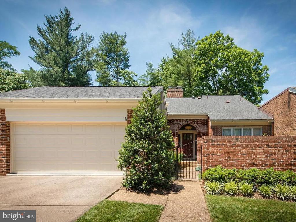 Single-story brick home with a white double garage door and gated front walkway.