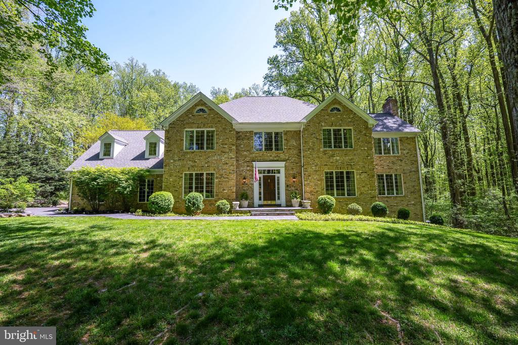 Two-story brick house with gabled roof, broad lawn, and mature trees.