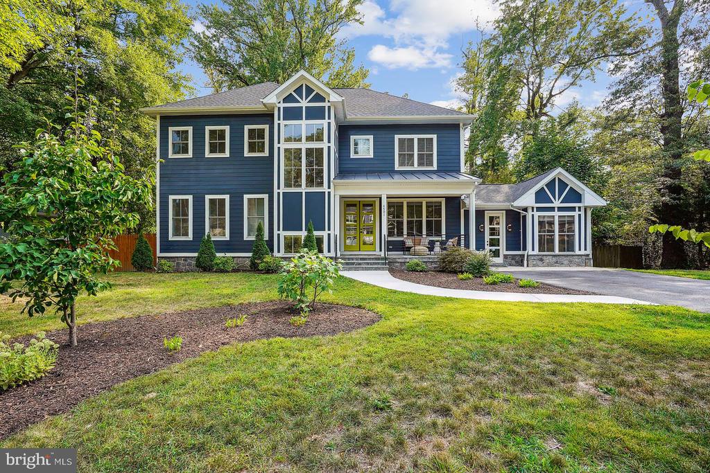 Navy-blue two-story house with white trim, a central glass gable, and landscaped front yard.