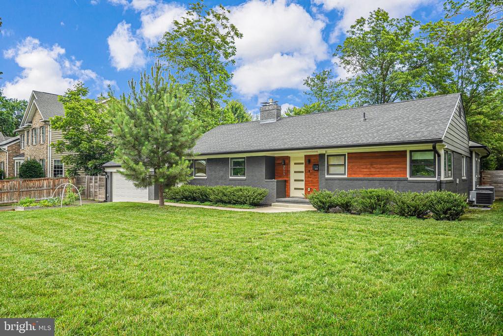 Gray ranch-style home with a broad lawn, attached garage, and landscaped front entry.