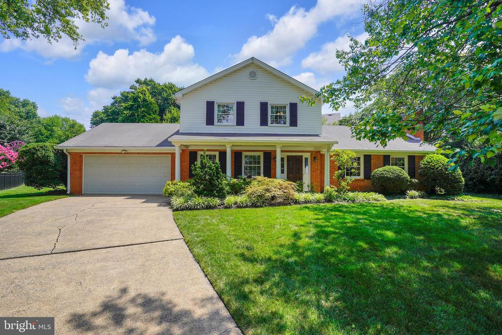 Two-story brick-and-siding house with a covered porch, attached garage, and landscaped front lawn.