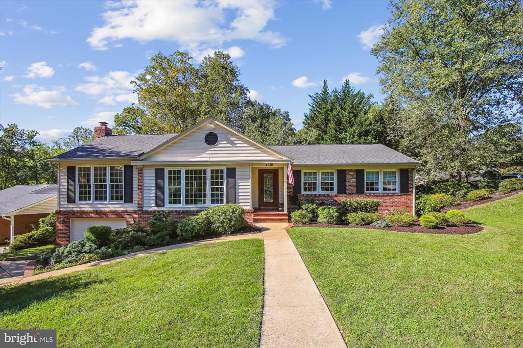 One-story brick-and-siding home with dark shutters, landscaped shrubs, and a walkway across the front lawn.