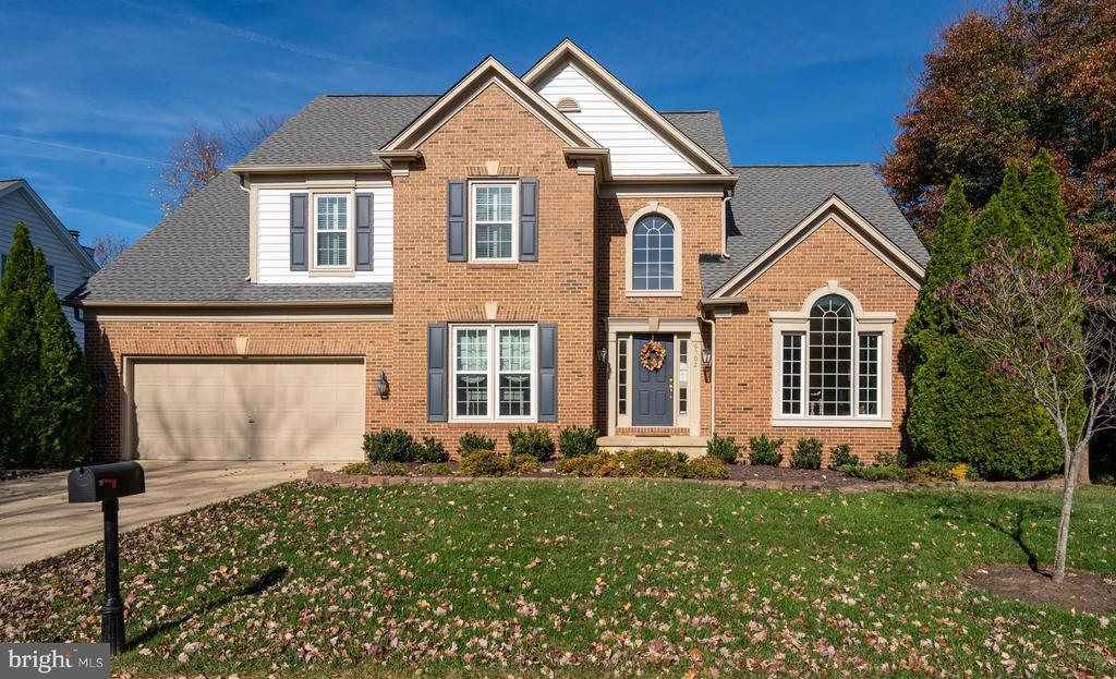 Two-story brick house with white siding accents, an attached garage, and a broad front lawn.