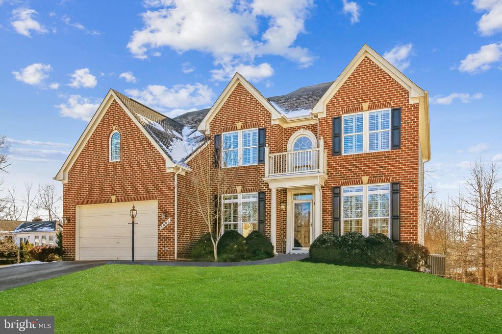 Two-story red-brick home with a front-facing garage and small balcony.