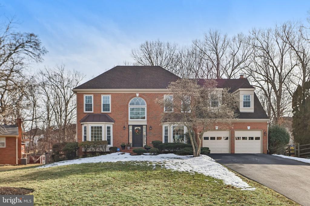 Two-story red-brick house with an arched entry window and attached two-car garage, photographed in winter.
