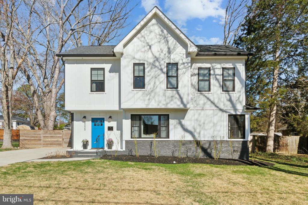 Two-story white house with a steep gable, blue front door, and gray masonry foundation.