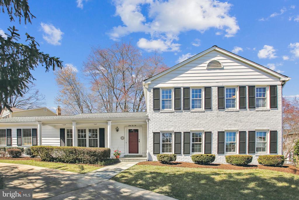 White two-story house with black shutters, a red front door, and a single-story wing.