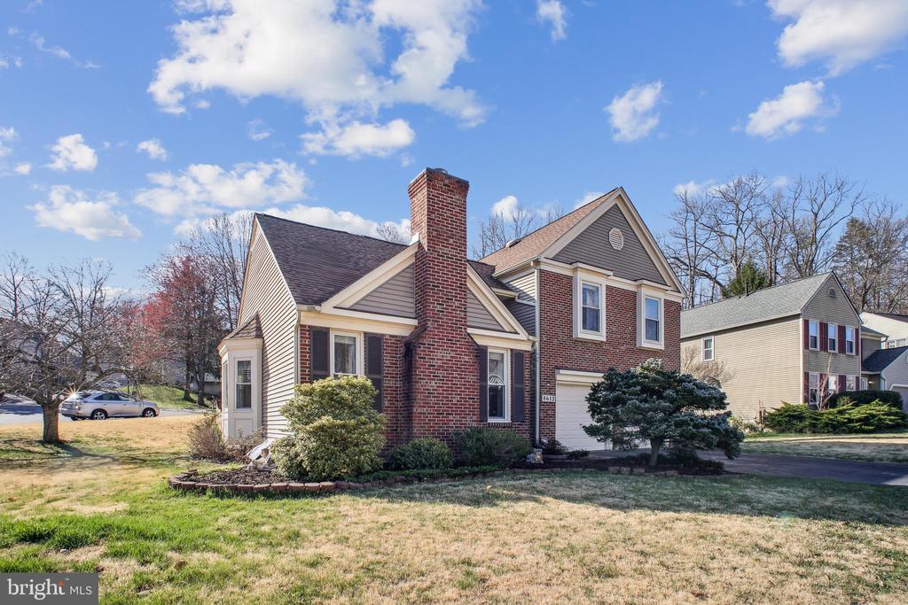 Two-story brick and gray-sided home with a tall chimney and attached garage.