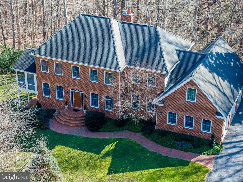 Aerial view of a large red-brick house with a slate-blue roof and curved brick walkway.